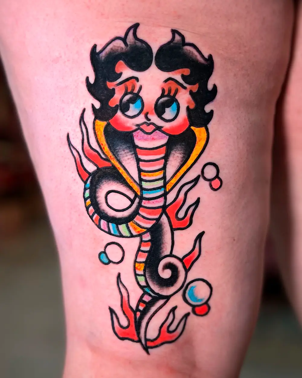 Tatuaje de cobra con cara de Betty Boop entre llamas