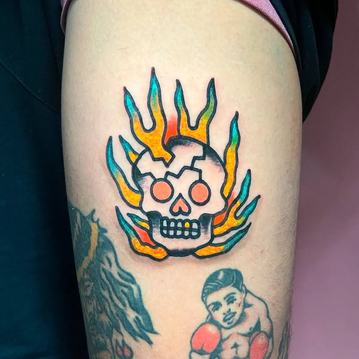 Tatuaje de calavera rodeada de llamas en degradado turquesa y naranja