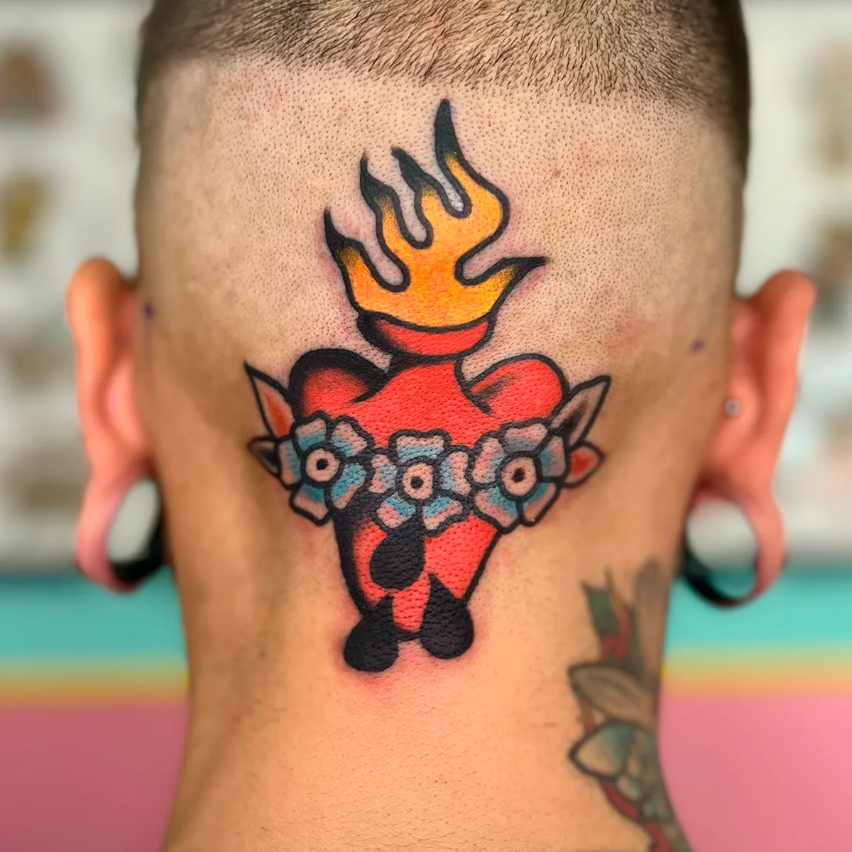 Tatuaje de corazón en llamas con flores en la nuca