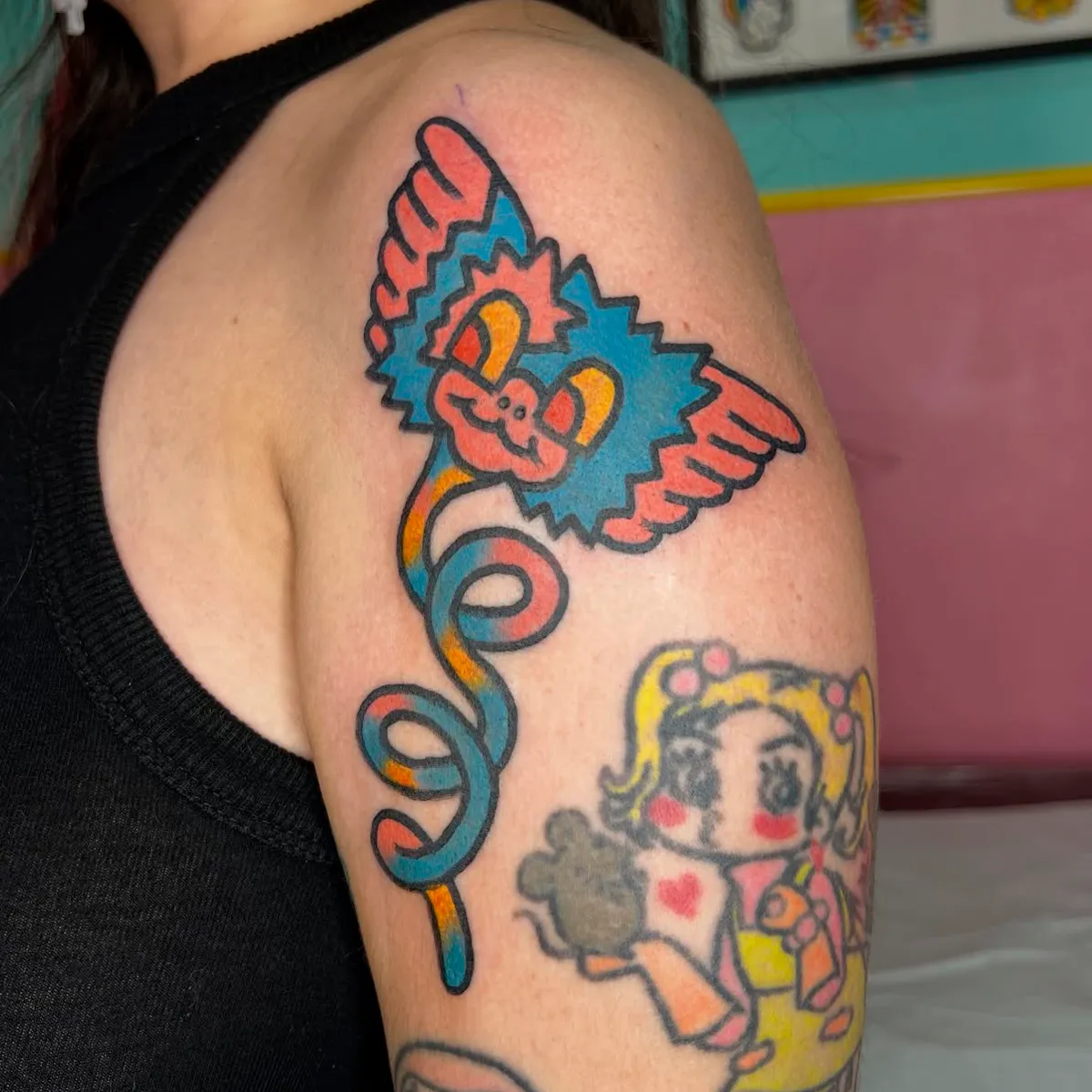 Tatuaje de mono alado con serpentina en el hombro