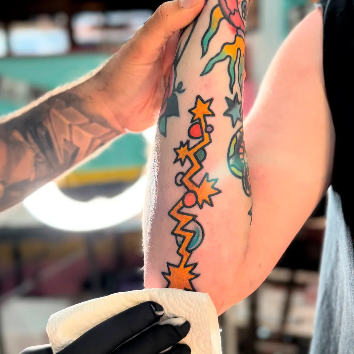 Tatuaje de rayo naranja con estrellas en el brazo