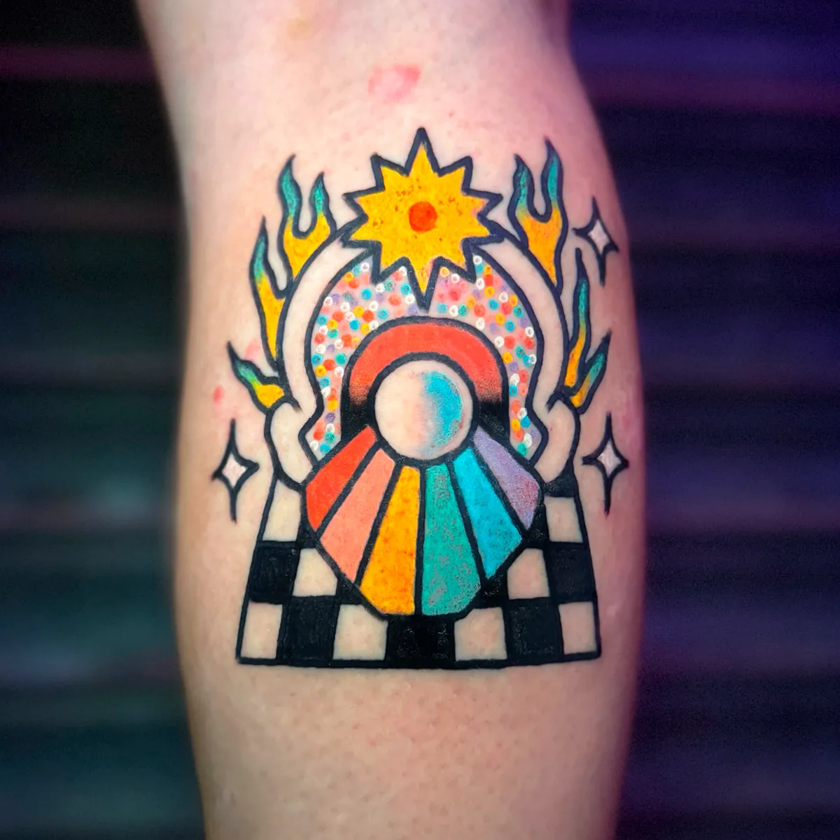 Tatuaje de sol con abanico de colores sobre suelo ajedrezado